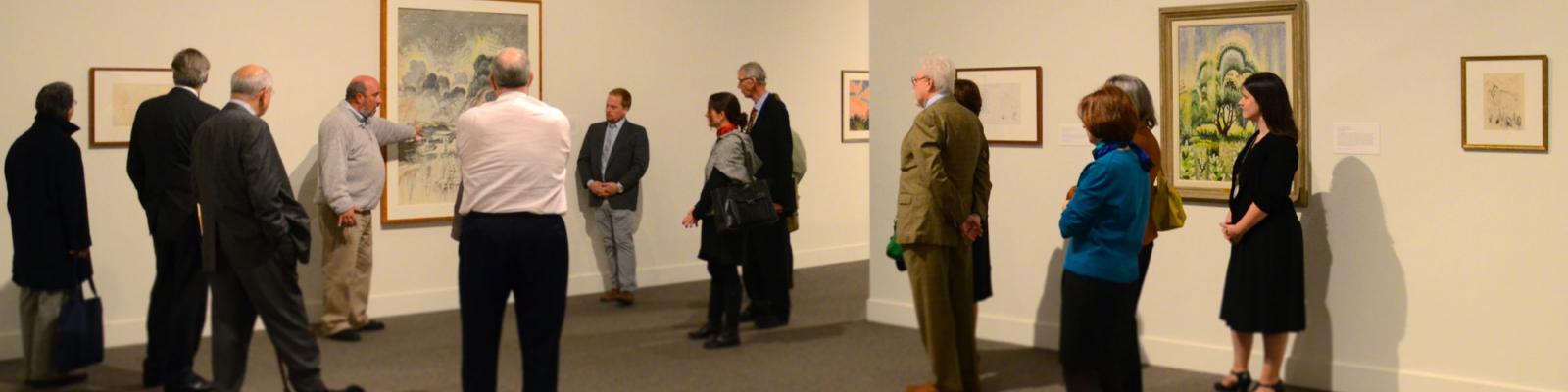 People standing in West Hall listening to gallery talk